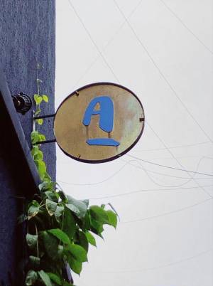 Site Practice - Signage in brass overgrown by greenery along the facade. Photo: Adrienne Thadani